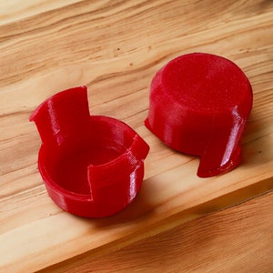 Peut inclure: Deux objets en plastique rouge imprimés en 3D. Un objet est un disque rond et l'autre est un objet en forme de tasse.