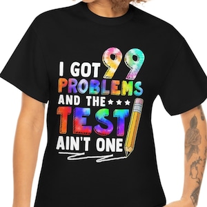 May include: Black t-shirt with a rainbow-coloured graphic that says "I got 99 problems and the test ain't one". A pencil is drawn next to the text.