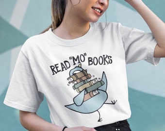 May include: White t-shirt with a blue bird carrying a stack of books. The text "READ "MO" BOOKS" is printed on the shirt.
