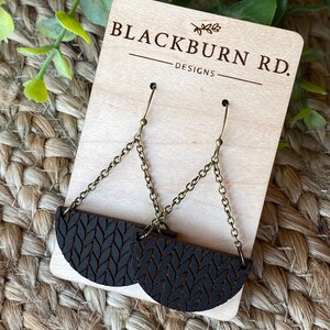 May include: Blackburn Rd. Designs earrings with a black wood knit pattern and gold chain.