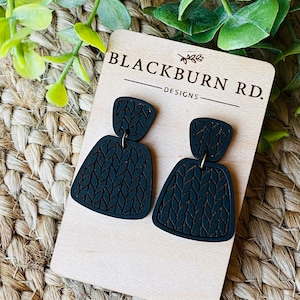 May include: Blackburn Rd. Designs earrings with a black knit pattern. The earrings are made of wood and have a simple, modern design.