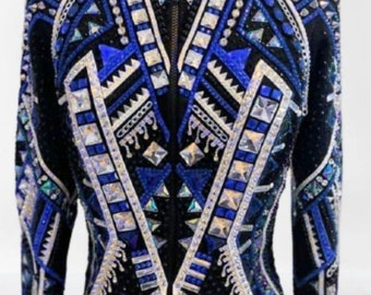 Könnte beinhalten: Eine schwarze, blaue und weiße Showjacke mit geometrischem Muster und Strasssteinen. Die Jacke hat einen Reißverschluss und lange Ärmel.