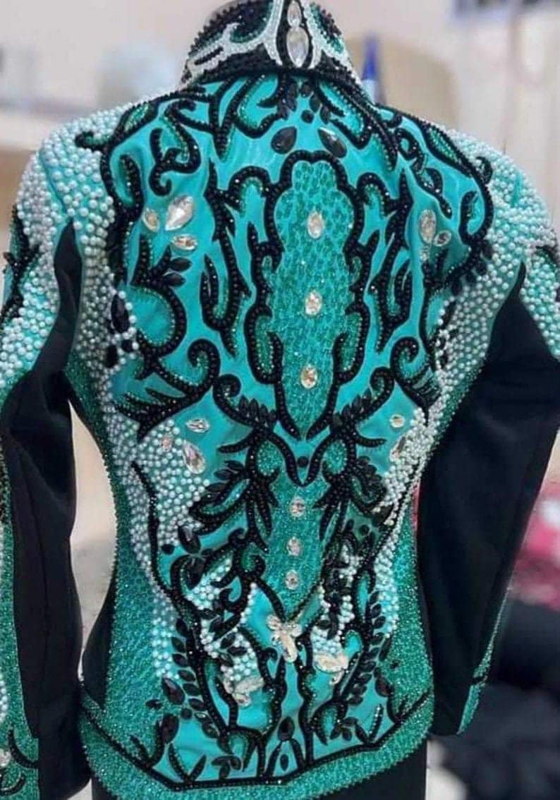 May include: A turquoise and black show jacket with intricate beading and embroidery. The jacket features a floral design with a butterfly in the center.