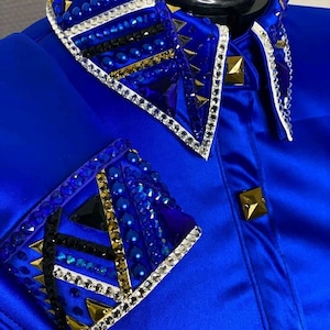May include: A royal blue satin shirt with a decorative collar and cuff. The collar and cuffs are adorned with rhinestones, gold accents, and black and white geometric patterns.