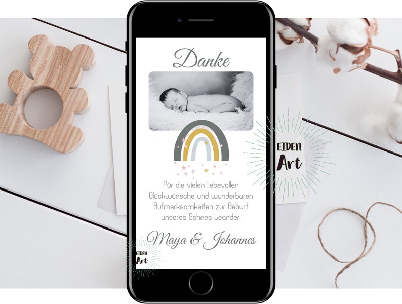 May include: A smartphone screen displaying a thank you card with a rainbow and stars design. The card says "Danke" and "For the many loving wishes and wonderful attentions for the birth of our son Leander. Maya & Johannes." The card also has a logo that says "EIDEN Art".