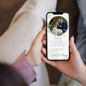 May include: A smartphone displaying a thank you message with a photo of a bride and groom in a circle surrounded by green foliage. The message reads "DANKE FUR DIE VIELEN WUNDERVOLLEN GESCHENKE GELUNGENEN &Uuml;BERRASCHUNGEN UND LIEBEVOLLEN GL&Uuml;CKW&Uuml;NSCHE ZU UNSERER HOCHZEIT WIR HABEN UNS SEHR DAR&Uuml;BER GEFREUT Lena & Philipp"