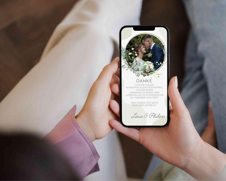 May include: A smartphone displaying a thank you message with a photo of a bride and groom in a circle surrounded by green foliage. The message reads "DANKE FUR DIE VIELEN WUNDERVOLLEN GESCHENKE GELUNGENEN &Uuml;BERRASCHUNGEN UND LIEBEVOLLEN GL&Uuml;CKW&Uuml;NSCHE ZU UNSERER HOCHZEIT WIR HABEN UNS SEHR DAR&Uuml;BER GEFREUT Lena & Philipp"