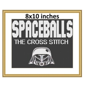 May include: Framed cross-stitch art piece with the text "SPACEBALLS THE CROSS STITCH" in white block letters. Below the text is a white helmet design. The framed art measures 8x10 inches.