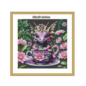 Peut inclure: Une œuvre d'art au point de croix encadrée représentant un dragon fantaisiste dans une tasse à thé, entouré de fleurs roses et de feuillage vert. L'œuvre mesure 25,4 x 25,4 cm et est encadrée d'or. Le dragon est rose, vert et violet.