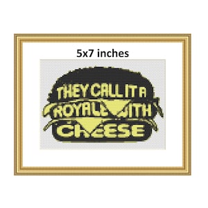 May include: A black and yellow cross-stitch pattern of a burger with the text "They call it a Royale with cheese". The pattern is framed in a gold frame and measures 5x7 inches.