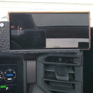 May include: A black phone is mounted in a car using a black and grey phone mount. The phone screen shows a battery icon with 97% and the text "3 mi until full". The car's dashboard is visible in the background.