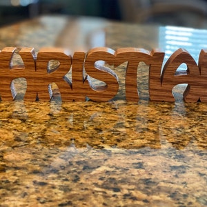 May include: Wooden name sign spelling "Christian" in a decorative font. The letters are made of light brown wood with a natural grain pattern.