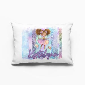Puede incluir: Cojín rectangular blanco con un diseño colorido que presenta un hada con cabello castaño y un vestido rosa. El nombre "Katelynn" está escrito en escritura púrpura. El fondo tiene rayas verticales en tonos de azul, morado y rosa.