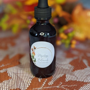 May include: A dark brown glass bottle with a black dropper top. The bottle has a white label with the text "Mycology Botanicals Turmeric & Black Pepper".