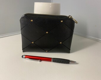 Può includere: Una pochette in pelle nera con cerniera, dettagli dorati e un motivo trapuntato a forma di diamante.