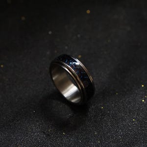 May include: A silver spinning ring with a blue and black patterned band.