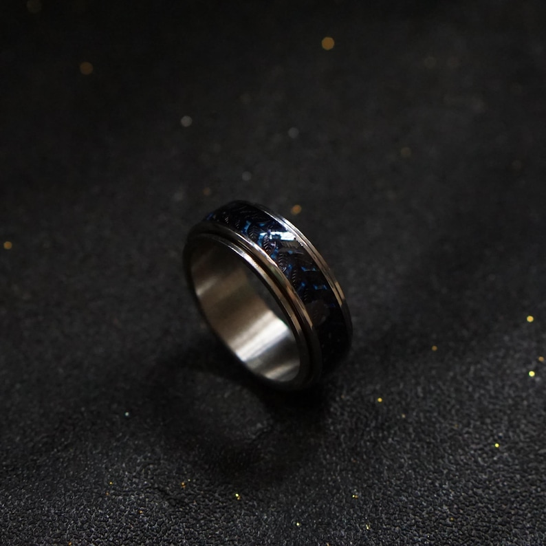 May include: A silver spinning ring with a blue and black patterned band.