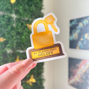 May include: A yellow and brown sticker with a padlock and key design. The sticker says "#1 FLASHLIGHT HOLDER".