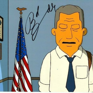 May include: A cartoon illustration of a man with a serious expression, wearing a white shirt and a blue tie. He is standing in front of an American flag hanging on a wall. The image is signed "B.D. Gray".