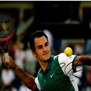 May include: A professional tennis player wearing a green and white shirt swings a red and black tennis racket. A yellow tennis ball is in the air.