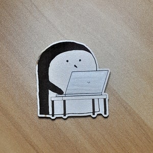 May include: A black and white illustration of a penguin sitting at a desk with a laptop. The penguin has a simple face with two eyes and a beak.