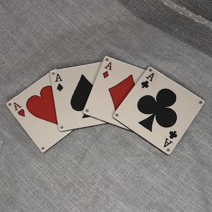 May include: Four playing cards, each with a different suit: hearts, diamonds, spades, and clubs. Each card is an ace and has a white background with black and red details.