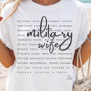 May include: A white t-shirt featuring black text that reads Military wife, Deployment cycles, Homefront strength, Care packages, Countdown calendars, Late night calls, Base life, Community bonds, Silent sacrifice, Proud support, Reunion tears, Holding it together, Flexible plans, Emotional endurance, Waiting patiently, Letters cherished, Holiday adjustments, Steady courage, All the tears and courage of a Spouse Loving a Hero.