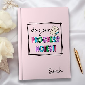 May include: Pink notebook with the text "do your PROGRESS NOTES!!" in colorful letters inside a black frame. The name "Sarah" is written at the bottom of the notebook.