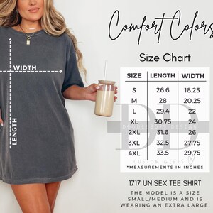 Op de afbeelding: Donkergrijs unisex T-shirt met maattabel. De maattabel toont afmetingen in inches voor maten S tot 4XL. Het shirt is gelabeld als een 1717 Unisex T-shirt.