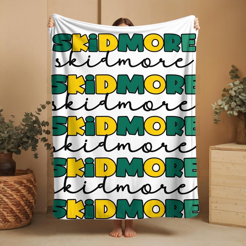 May include: White fleece blanket with the word "SKIDMORE" repeated in green and yellow lettering.
