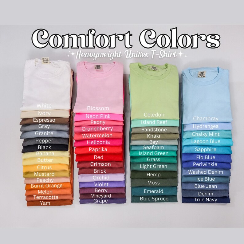 Op de afbeelding: Stapels Comfort Colors unisex T-shirts van zware kwaliteit in diverse kleuren, waaronder wit, roze, groen en blauw. Elke stapel toont een andere kleur met de bijbehorende naam. De afbeelding toont een breed scala aan tinten.