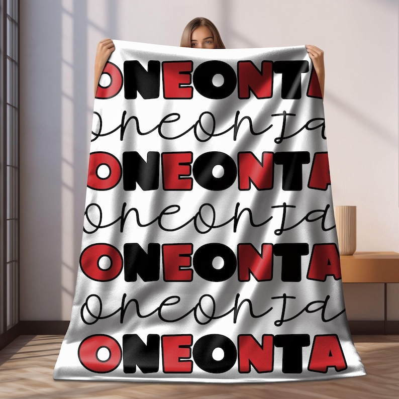 May include: White fleece blanket with the word "ONEONTA" repeated in red and black lettering. The word "oneonta" is written in cursive in black lettering.