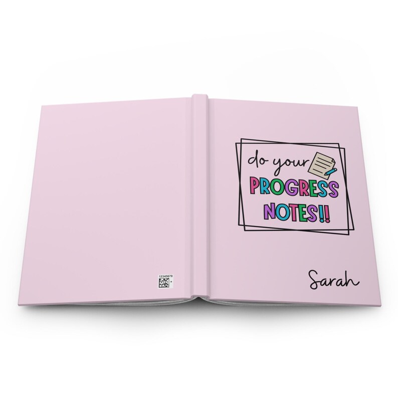 Op de afbeelding: Een roze notitieboekje met de tekst "do your PROGRESS NOTES!" in kleurrijke letters. Het notitieboekje is open op een lege pagina en heeft de naam "Sarah" op de rechterpagina.