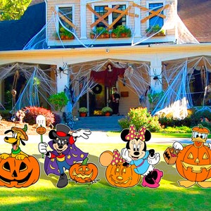 May include: Four Halloween yard decorations featuring Mickey Mouse, Minnie Mouse, Donald Duck, and Goofy. Each character is dressed in a Halloween costume and holding a jack-o'-lantern.