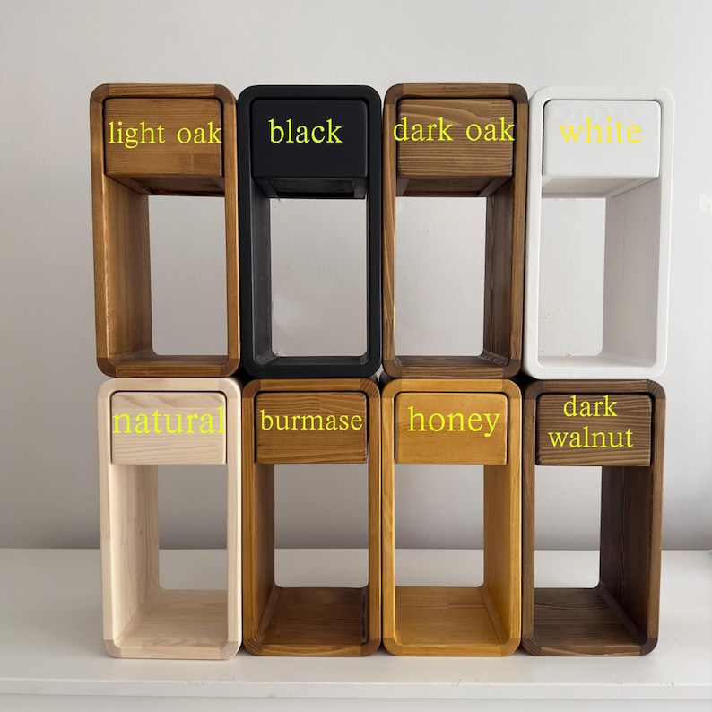 Puede incluir: Una colecci&oacute;n de ocho mesitas de noche de madera peque&ntilde;as en varios colores. Los colores incluyen roble claro, negro, roble oscuro, blanco, natural, birmano, miel y nogal oscuro. Cada mesita tiene un caj&oacute;n.