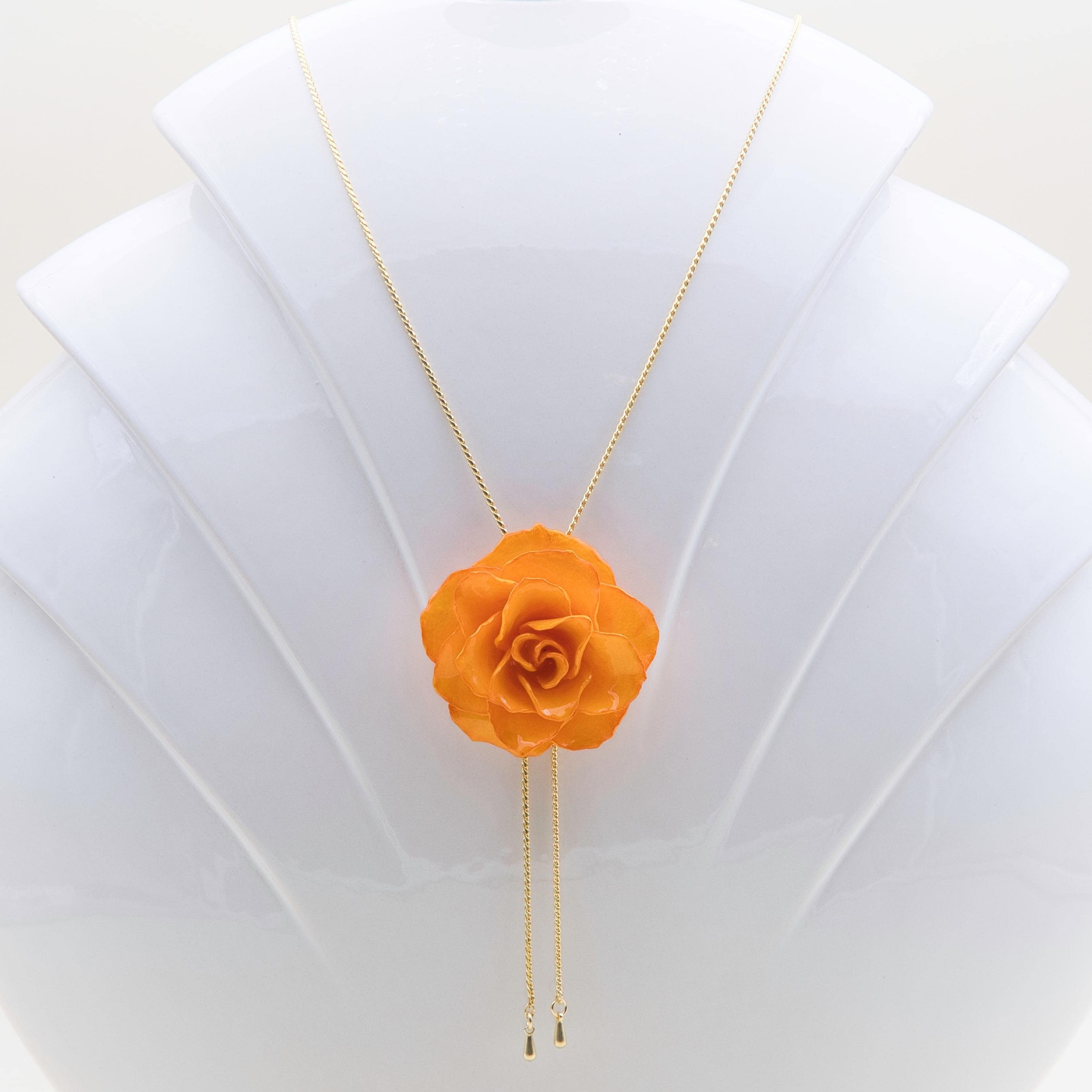 オレンジ色の本物のバラが付いた金メッキのネックレス。特別な人への