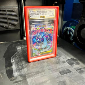 May include: A graded Japanese Mega Charizard X EX card in a red protective case. The card features the text "INFERNOX" and other Japanese text. The case is graded GEM-MT 10 by AGS.