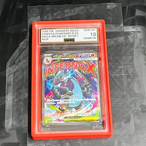 May include: A graded Pok&eacute;mon card featuring a Charizard EX. The card is encased in a red holder with the text "2026 P.M. JAPANESE MEGA FA/MEGA CHARIZARD X EX MEGA DREAM EX SECRET #223" and "GEM-MT 10". The card art displays a blue and black Charizard with the text "INFERNO X".