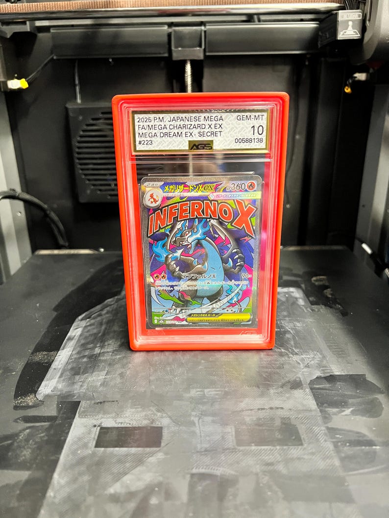 May include: A graded Japanese Mega Charizard X EX trading card in a red protective case. The card features a colorful illustration of a dragon-like creature with the text "INFERNOX". The case has a GEM-MT 10 grade.