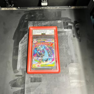 May include: A graded Japanese Mega Charizard X EX Secret card in a red holder. The card features a colorful illustration of a dragon-like creature with the text "INFERNO X". The card is graded GEM-MT 10.