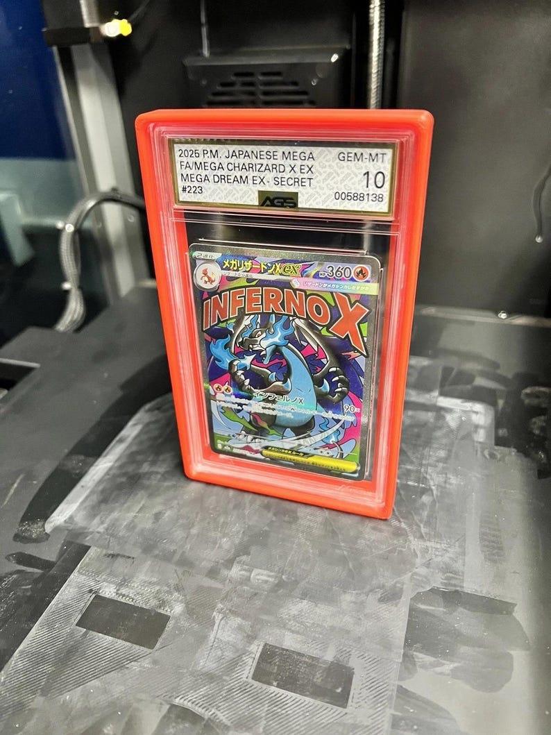 May include: A graded Japanese Mega Charizard X EX card in a red plastic case. The card is graded GEM-MT 10 by AGS. The card features the text "INFERNO X" and Japanese text.