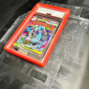May include: A graded trading card in a red plastic case. The card features a colorful illustration of a dragon with the text "Inferno X". The case is labeled with text including "GEM-MT 10".