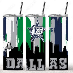 Puede incluir: Un vaso de acero inoxidable con un logotipo de los Dallas Cowboys y un dise&ntilde;o de ciudad. El vaso tiene un fondo blanco con salpicaduras de pintura verde, azul y gris. El texto "DALLAS" est&aacute; impreso en gris en la parte inferior del vaso.