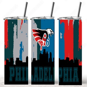 Puede incluir: Un vaso de acero inoxidable con un dise&ntilde;o de los Philadelphia Eagles. El vaso presenta un &aacute;guila roja, blanca y azul con el logotipo del equipo, una ciudad y la palabra "PHILADELPHIA" en una fuente verde.