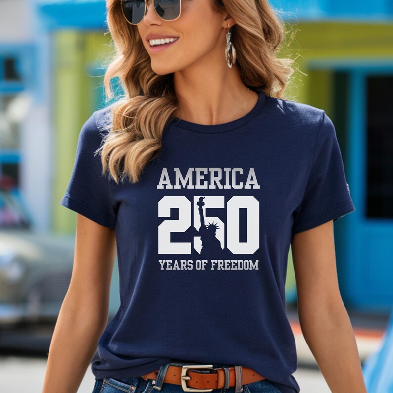 Puede incluir: Camiseta azul marino con el texto blanco "AMERICA 250 YEARS OF FREEDOM". El n&uacute;mero 250 est&aacute; en negrita, con la silueta de la Estatua de la Libertad. La camiseta tiene mangas cortas y cuello redondo.
