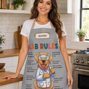 May include: A gray apron with the text "LAB RULES" in colorful letters. The apron features a cartoon dog wearing lab goggles and a lab coat, holding a test tube. The apron also has the name "Jennifer" on it.