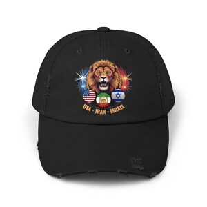 Puede incluir: Gorra de béisbol negra desgastada con un gráfico de león y las banderas de EE. UU., Irán e Israel. El diseño incluye el texto "USA - IRAN - ISRAEL" en una disposición circular alrededor de las banderas.