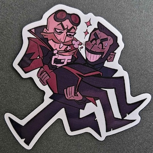 Può includere: Un adesivo con un'illustrazione di due personaggi dei cartoni animati. Un personaggio indossa una giacca rosso e nera e tiene una tazza. L'altro personaggio indossa un abito nero e tiene il primo personaggio tra le braccia. Lo sfondo è bianco.