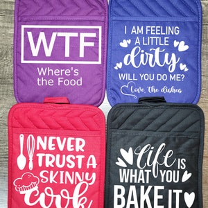 May include: Four quilted pot holders in purple, blue, red, and black. Each has a pocket and a loop for hanging. The purple one says "WTF Where's the Food." The blue one says "I am feeling a little dirty." The red one says "Never trust a skinny cook." The black one says "Life is what you bake it."