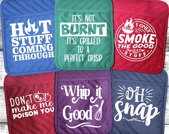 Könnte beinhalten: Satz von sechs bunten Topflappen mit lustigen Sprüchen. Die Sprüche lauten: "Hot Stuff Coming Through", "It's Not Burnt It's Grilled to a Perfect Crisp", "I Only Smoke the Good Stuff", "Don't Make Me Poison You", "Whip it Good" und "Oh Snap".